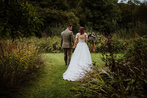 A couple walking round the pond at Knightor following their ceremony