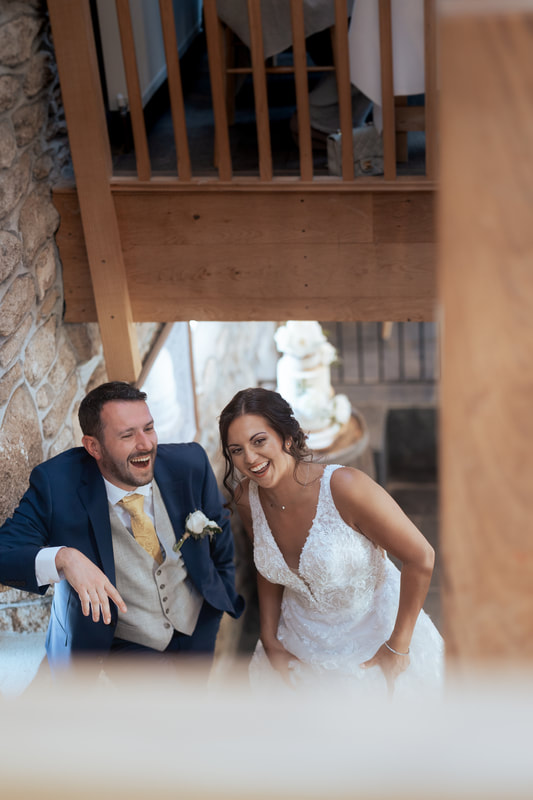 A couple laughing on the stairs in the rustic barn